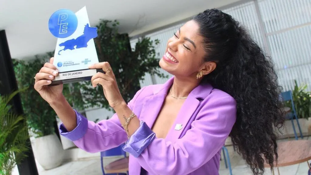 Joyce segurando a placa do Prêmio recebido pela Prefeitura do Rio.