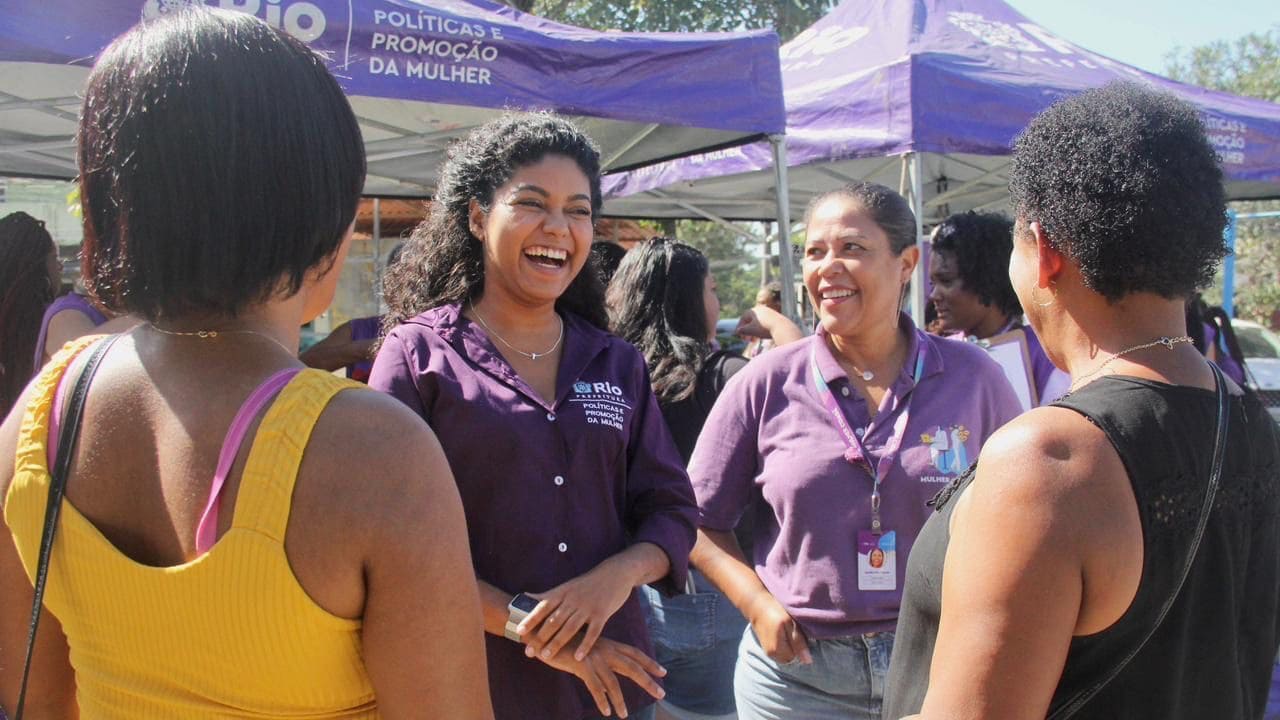 Joyce Trindade sorrindo,atendendo a várias mulheres na rua